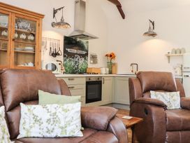 A living room with a sofa, kitchen cabinet, and stove at The Forge in Falmouth