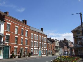 A street with brick buildings a flower bed and road signs at Lakeview Yurt in Beckford near Tewkesbury
