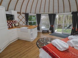 A yurt interior with a kitchen area bed with robes and towels and patio doors opening to outdoor chairs at Lakeview Yurt Beckford near Tewkesbury