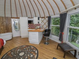 A yurt interior with a small kitchen counter and two bar stools next to windows and a round decorative rug on the floor at Lakeview Yurt in Beckford near Tewkesbury