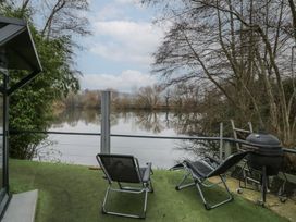 A river view with two reclining chairs and a barbecue on a deck at Lakeview Yurt in Beckford near Tewkesbury