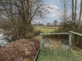 Two metal chairs on a small outdoor deck overlooking a grassy field and trees at Lakeview Yurt in Beckford near Tewkesbury