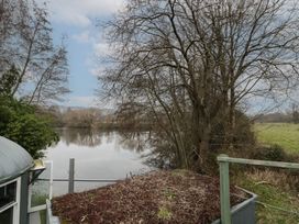 A river with trees and bushes along the bank viewed from a structure with a green roof at Lakeview Yurt in Beckford near Tewkesbury