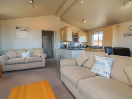 A living room with beige sofas and kitchen area at 1 Ocean Terrace Ilfracombe