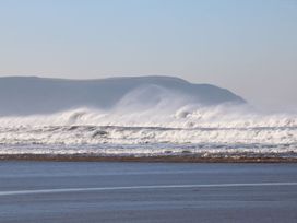 Ocean waves crashing on a beach with hills in the background at 1 Ocean Terrace Ilfracombe