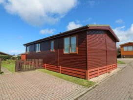 A brown wooden house with windows and a fence at 1 Ocean Terrace Ilfracombe