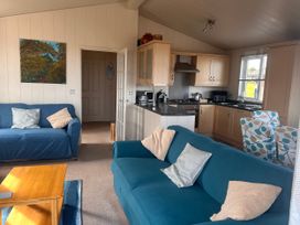 A living room with couches and kitchen area at 1 Ocean Terrace Mullacott near Ilfracombe