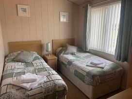 A bedroom with two single beds and a window at 1 Ocean Terrace, Mullacott near Ilfracombe