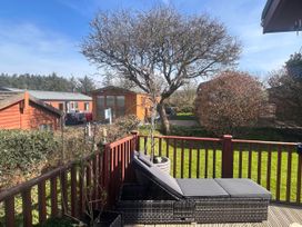 An outdoor patio with a lounge chair and trees at 1 Ocean Terrace Mullacott near Ilfracombe