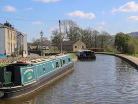 A canal with two boats and houses alongside at The Summerhouse in Kildwick