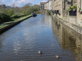 A canal with ducks and boats and houses alongside at The Summerhouse in Kildwick