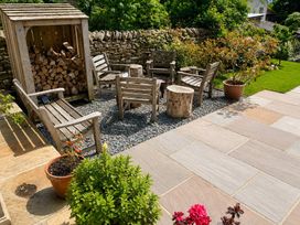 A seating area with wooden chairs and firewood storage at The Summerhouse in Kildwick