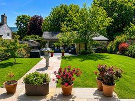 A garden with grass, flower pots, and a house at The Summerhouse in Kildwick