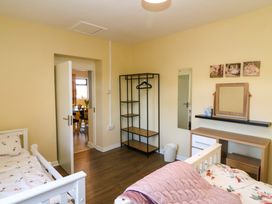 A bedroom with a bed, shelf, mirror, and a coat rack at Thadg and Hannah’s in Miltown