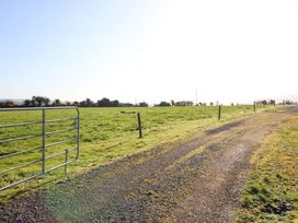 A grassy field with a gate and gravel path at Thadg and Hannah’s in Miltown