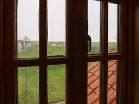 A view from a window showing grass, houses, and a path at Mabby in Caister-On-Sea