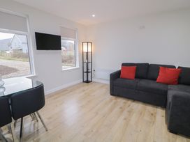 A living room with a sofa, table, and television at Binevenagh Point Cabin