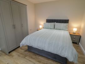 A bedroom with a bed, wardrobe, nightstand, and lamp at Binevenagh Point Cabin