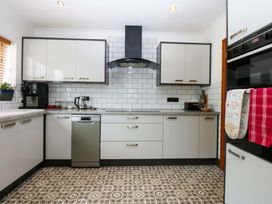 A kitchen with cabinets and appliances at 36 Cae Rhos in Holyhead