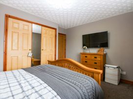 A bedroom with a bed, wardrobe, television, and dresser at 36 Cae Rhos Holyhead