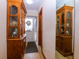 A hallway with a display cabinet and door at 36 Cae Rhos in Holyhead