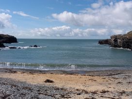 A beach with water and rocks at 36 Cae Rhos in Holyhead