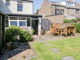A garden with a dining table, chairs, and a shed at Yewbarrow in Seascale