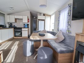 A kitchen and dining area with a sofa and table at Chappie's Caravan in Rhyl