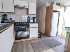 A kitchen with appliances and cabinets at Chappie's Caravan in Rhyl