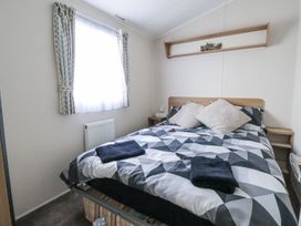 A bedroom with a bed and window at Chappie's Caravan Rhyl
