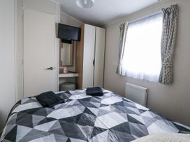 A bedroom with a bed and television at Chappie's Caravan in Rhyl