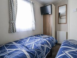 A bedroom with two beds and a television at Chappie's Caravan in Rhyl