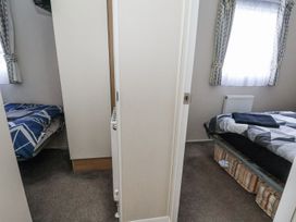 A bedroom with two beds and a wardrobe at Chappie's Caravan in Rhyl