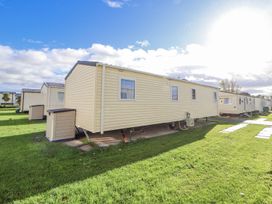 A caravan with windows and surrounding grass at Chappie's Caravan in Rhyl