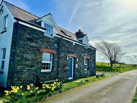 A house with a blue door and a flower bed at Penpegws near Aberystwyth