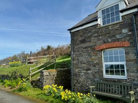A stone house with a window and flowers in a garden at Penpegws near Aberystwyth