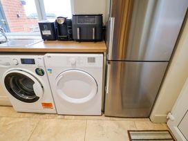 A kitchen with a washing machine and dryer next to a refrigerator at Cliff Cottage