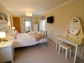 A bedroom with bed, dresser, and television at Cliff Cottage