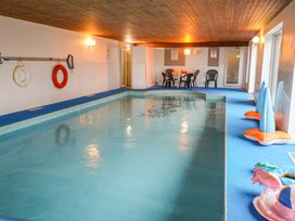 An indoor pool with chairs and a table at Cliff Cottage 