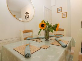 A dining room with a table and sunflowers in a vase at 8 Railway Cottages in Ulverston
