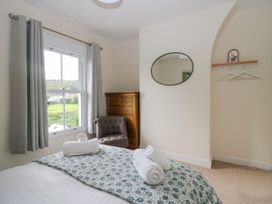 A bedroom with a bed and chair at 8 Railway Cottages in Ulverston