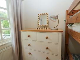 A dresser with a lamp and mirror in a bedroom at 8 Railway Cottages in Ulverston
