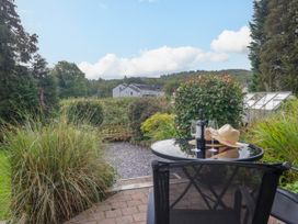 A garden with a table and chairs holding wine and a hat at 8 Railway Cottages Ulverston
