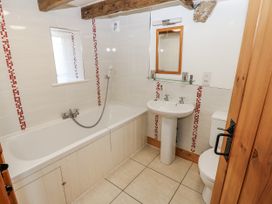 A bathroom with a bathtub, toilet, sink, and mirror at Dove Cottage in Hexham