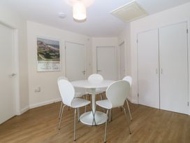 A dining room with a round table and white chairs at Orme View Penmaenmawr