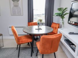 A dining room with a round table and orange chairs at 16 The Viking Seahouses