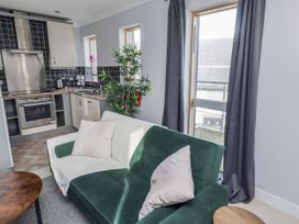 A living room with a sofa and kitchen area at 16 The Viking in Seahouses