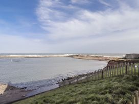 A coastal view with water and a wooden fence at 16 The Viking Seahouses