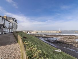 A view of a jetty and sea beside a building at 16 The Viking Seahouses