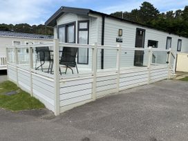 A caravan with a deck and chairs at WW15 Plot in Newquay